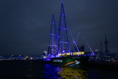 Rainbow Warrior vuosipäivän valaistuksessa Aucklandin satamassa Uudessa-Seelannissa. Greenpeacen työntekijät ja vapaaehtoiset pitelevät kirjaimia, jotka muodostavat ikonisen lauseen "You Can't Sink a Rainbow".