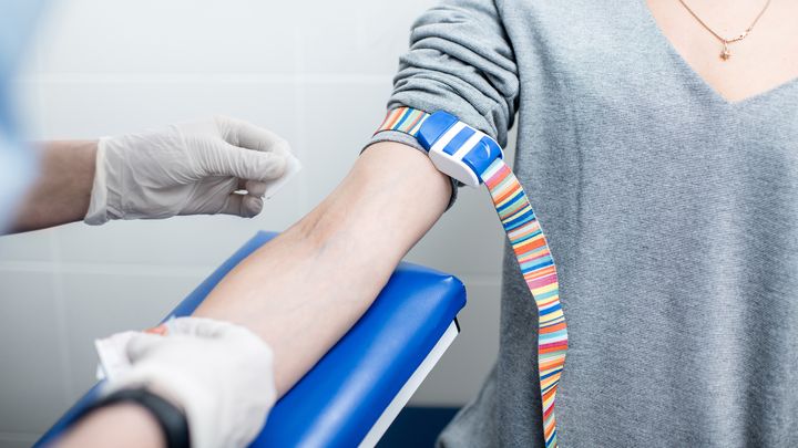 Hoitaja valmistautuu ottamaan verikoetta potilaan käsivarresta.