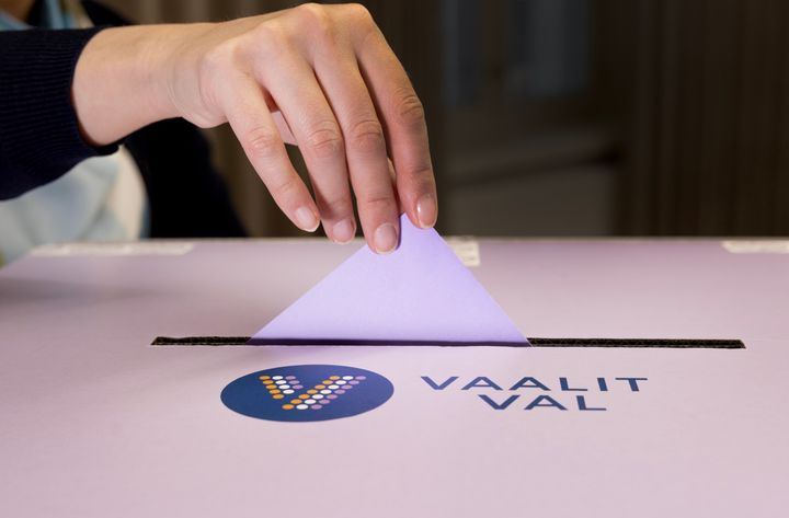 Henkilö asettaa äänestyslipukkeen vaaliuurnaan.