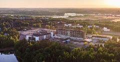 Ilmakuva laajasta, vehreästä alueesta, jossa on keskellä Kymenlaakson keskussairaala auringonnousussa.