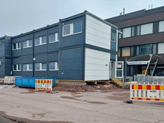 Kaksikerroksinen konttirakennus, jonka vieressä on rakennustyömää ja liikenne-esteitä.