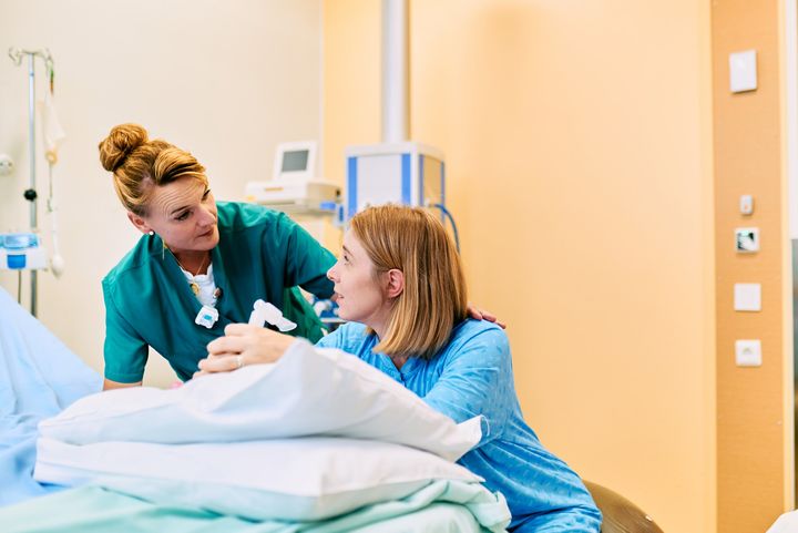 Kätilö juttelee raskaana olevalle naiselle synnytyssalissa.