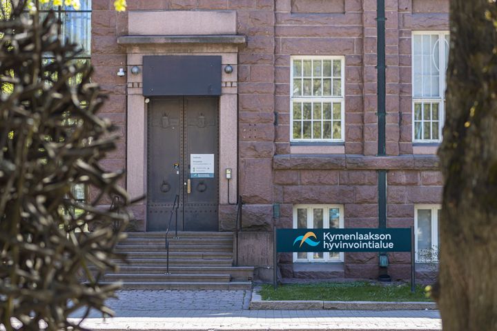 Kuva punatiilisestä rakennuksesta, jonka edessä opastekyltti "Kymenlaakson hyvinvointialue".