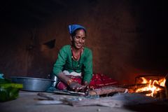 Nepalilainen pienviljeljä Deushara Nepali istuu keittiössään ja valmistaa ruokaa. Hänen vieressään on tulisija ja toisella puolella iso metallinen kulho.