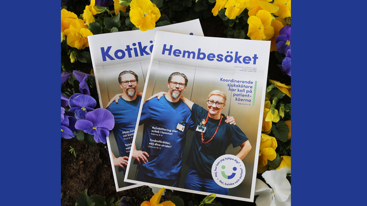 Kaksi Kotikäynti-lehteä kukkien keskellä.