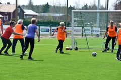 Joukko iäkkäitä ihmisiä pelaa jalkapalloa. Osalla on yllään oranssit liivit.