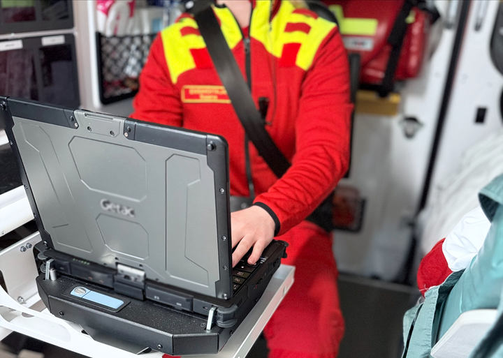 Akutvårdaren sitter i ambulansen och skriver text till maskinen.