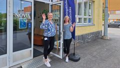 Kaksi ihmistä pitelee auki katutasossa olevaa ovea keltaiseen rakennukseen.