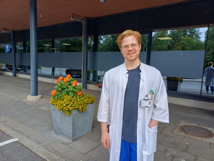 Lääkäri Simo Nuuttila hymyilee ja seisoo ulkona päivystysrakennuksen edessä.