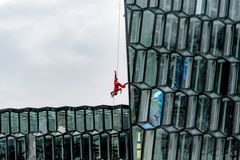 Sirkustaiteilija roikkuu lasitalon seinällä