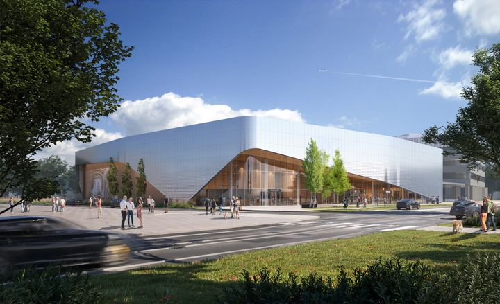 Moderni rakennus, jossa alumiini- ja lasijulkisivut sekä puuta. Rakennuksen muoto jäljittelee lentokoneiden liikkeitä. Eteen avautuu laaja piha, ja taustalla on sininen taivas.