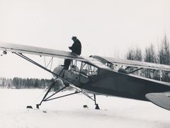Mies istuu lentokoneen siivellä lumiympäristössä.