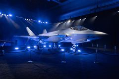 Kuvassa on F-35-hävittäjä roll out -tilaisuudessa. Taustalla on tummat valot ja hävittäjä on esillä näyttävästi valaistuna.