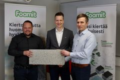 Kolme miestä pitelee uutta vaahtolasista valmistettua kattotuotetta kädessään Foamit Oyj:n tilaisuudessa. Taustalla on kaksi Foamit-logolla varustettua esittelytaulua.