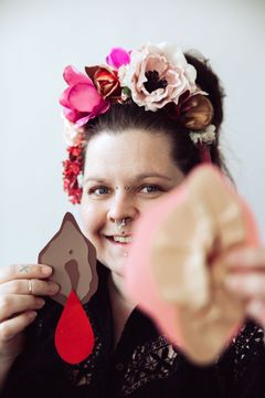 Let it flow -kuukautisoppaan suunnittelija Aino Nieminen kädessään paperista leikatut vulvat