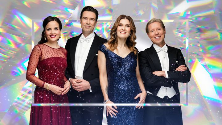 Neljä juhla-asuihin pukeutunutta hymyilevää henkilöä.