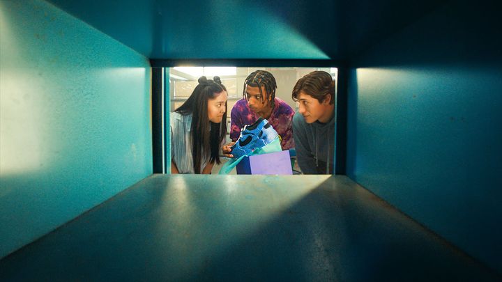 Kuva%20otettu%20laatikosta%20k%E4sin.%20Suuaukolla%20kolme%20nuorta%20katsoo%20toisiaan%20ja%20pitelee%20k%E4siss%E4%E4n%20sinist%E4%20lenkkaria.