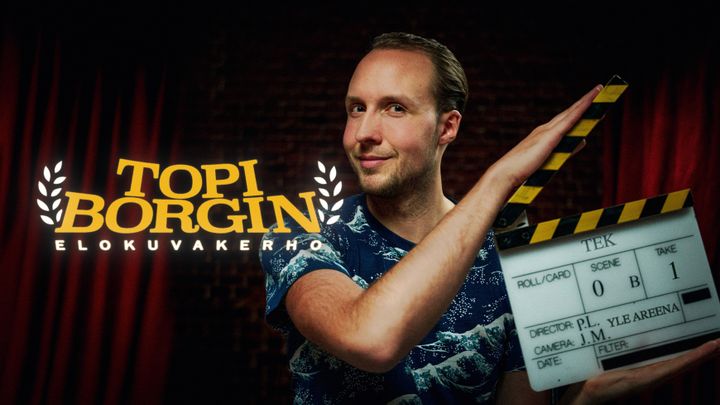 Topi Borg klaffin kanssa katsoo suoraan kameraan.