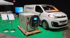 Alt-teksti: Suomen ensimmäisen tilauslatauspalvelun EV Mobile:n esittelypiste messuilla, jossa on tuotantolaitteisto ja pakettiauto.