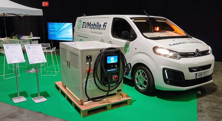 Alt-teksti: Suomen ensimmäisen tilauslatauspalvelun EV Mobile:n esittelypiste messuilla, jossa on tuotantolaitteisto ja pakettiauto.