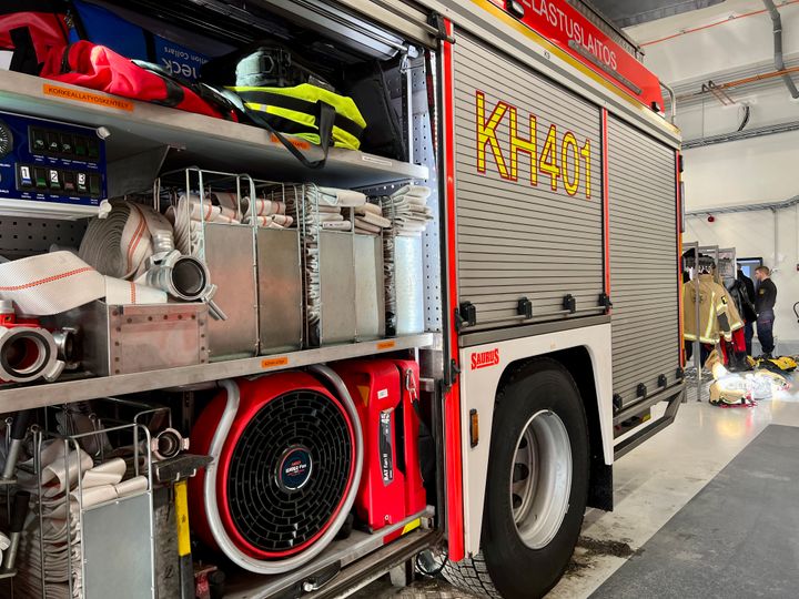 Paloauto avonaisilla tavaratiloilla, joissa on letkuja ja varusteita paloasemalla.