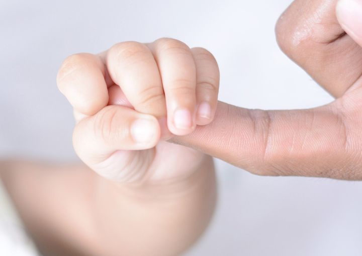 Vauvan käsi pitää aikuisen sormesta kiinni.