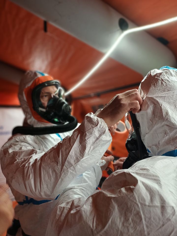 Pelastaja auttaa kollegalleen ylle suojapukua.