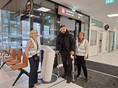 Kolme henkilöä seisomassa päivystyksen aulassa.