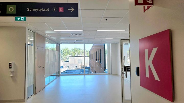 Kuva käytävästä, jolla on vaaleat seinät ja katto, sekä K-tunnus näkyvissä.