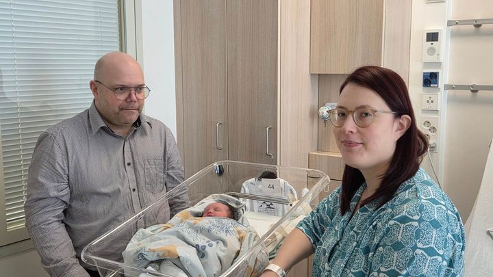 Kuvassa kaksi henkilöä seisoo vastasyntyneen vauvan vieressä sairaalassa.