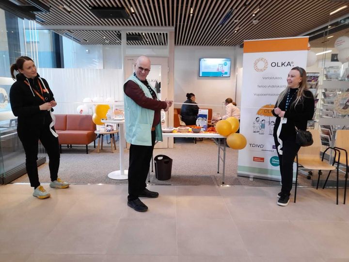 OLKA-pisteen avajaisien avajaisnauhaa  pitelee kaksi naishenkilöä ja leikkaamassa vapaaehtoisena työskentelevä mieshenkilö