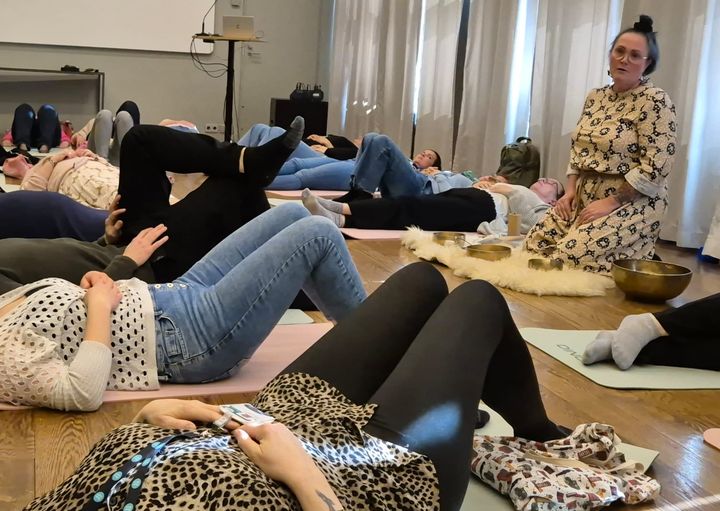 Christa%20Ahonen%20vet%E4m%E4ss%E4%20%E4%E4nimaljarentoutusta%20Oma%20H%E4meen%20henkil%F6st%F6lle.%20Ihmisi%E4%20makoilee%20joogamattojen%20p%E4%E4ll%E4%20salissa.