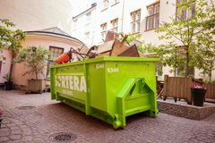 Vihreä Sorteran jätelava, jossa on sekalaista rakennusjätettä, sisäpihalla.