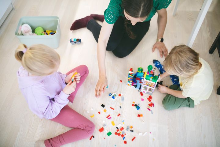 lapset ja äiti leikkivät yhdessä legoilla