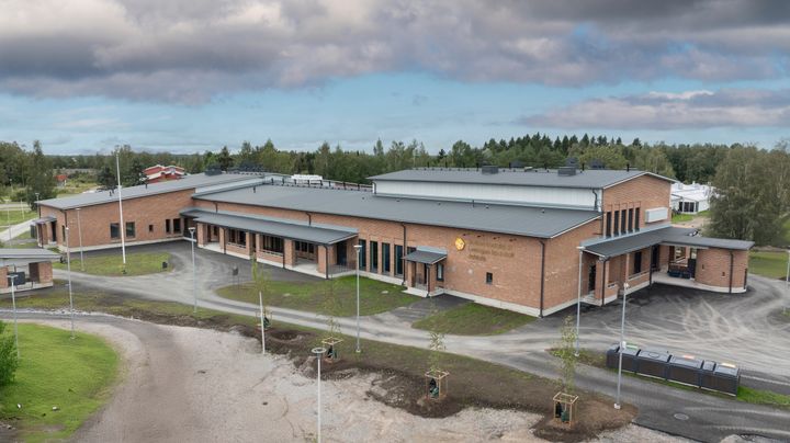 Ilmakuva punatiilisestä, yksikerroksisesta rakennuksesta.