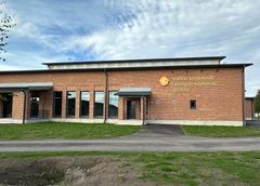 Punatiilinen yksikerroksinen rakennus, jossa on moderni muotoilu ja suuret ikkunat.