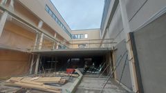Rakennuksen sisäpihan rakennustyömaa, jossa on keskeneräisiä rakenteita ja rakennusmateriaaleja.