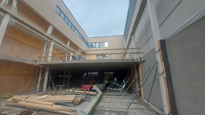 Rakennuksen sisäpihan rakennustyömaa, jossa on keskeneräisiä rakenteita ja rakennusmateriaaleja.