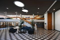 Kansallisarkiston aulatila, jossa on ruutukuvioinen lattia, harmaa katto ja oleskelualue sohvilla.