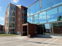 Kolmikerroksinen tiili- ja lasirakennus, jonka edustalla on Kallanranta 11 -kyltti.