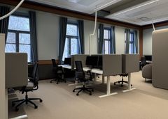 Avoin toimistotila, jossa on työpisteitä ja harmaita tuoleja.