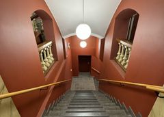 Portaat, joissa on katossa pyöreät valaisimet, punaiseksi maalattujen seinien keskellä.