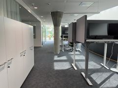 Työskentelytilat, joissa on säädettäviä työpöytiä ja kaappeja pitkän käytävän varrella.