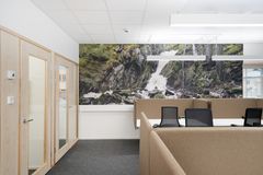 Tytila, jossa on työpöytiä, tuoleja ja luonnonaiheinen seinämaalaus vesiputouksesta.