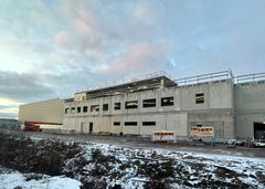 Rakenteilla olevan rakennuksen betoniulkoasu lumisessa ympäristössä.