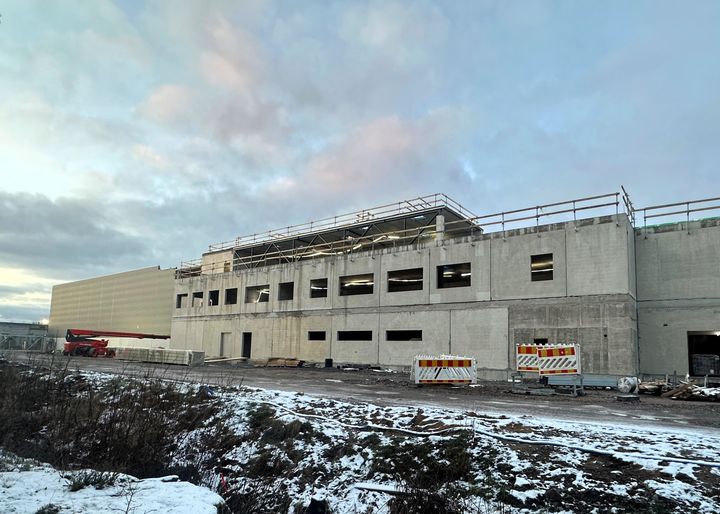 Rakenteilla olevan rakennuksen betoniulkoasu lumisessa ympäristössä.