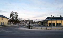 Aidan takana on kaksi keltaista rakennusta, joiden välissä on portti; oikeanpuoleisen rakennuksen seinässä lukee 'Rajasotilaskoti'.