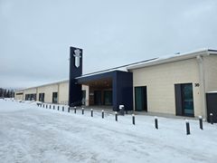 Vaalea rakennus, jossa on korkea sininen sisäänkäynti. Maassa lunta.