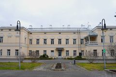 Suuri vaalea rakennus, jossa on kaariaukkoja ikkunoiden yläpuolella. Edessä pieni piha ja kaksi lyhtypylvästä.