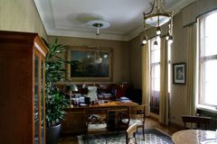 Vanhahtava toimisto, jossa on puuhuonekaluja, suuri kasvi, ja taulu seinällä.